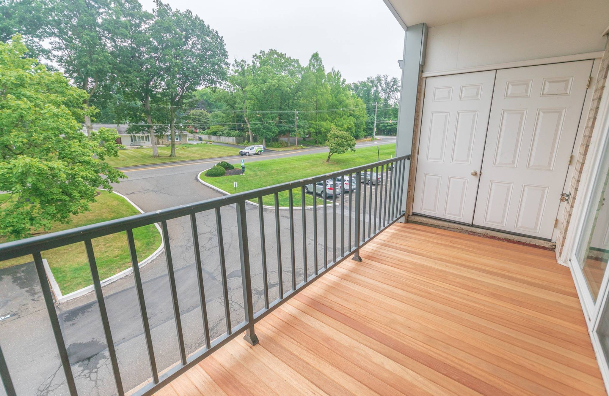 A large balcony overlooking the greenery and parking lot at Valley Stream Apartments
