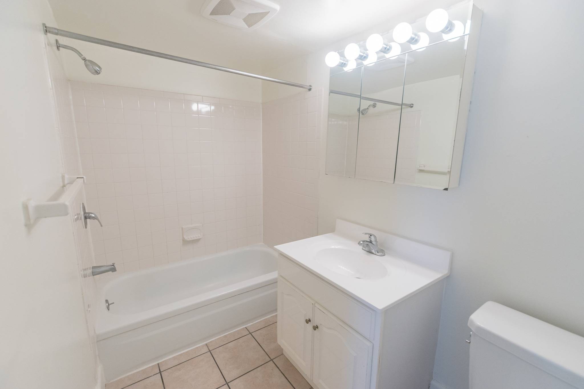 Bathroom area of an apartment, fitted with tiled flooring, a single vanity, and a shower