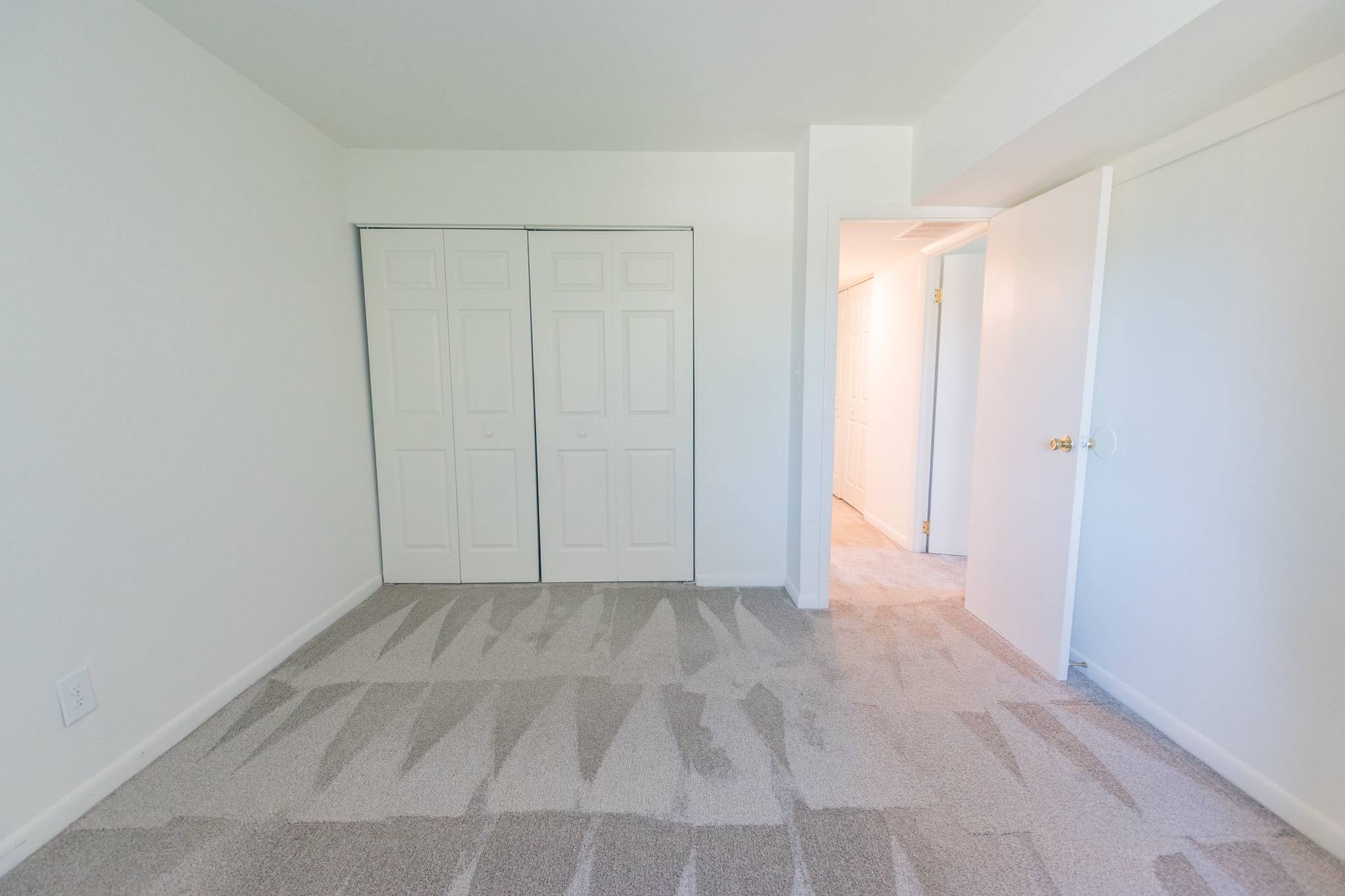 Bedroom area of an apartment unfurnished, fitted with carpet flooring, and a spacious closet space