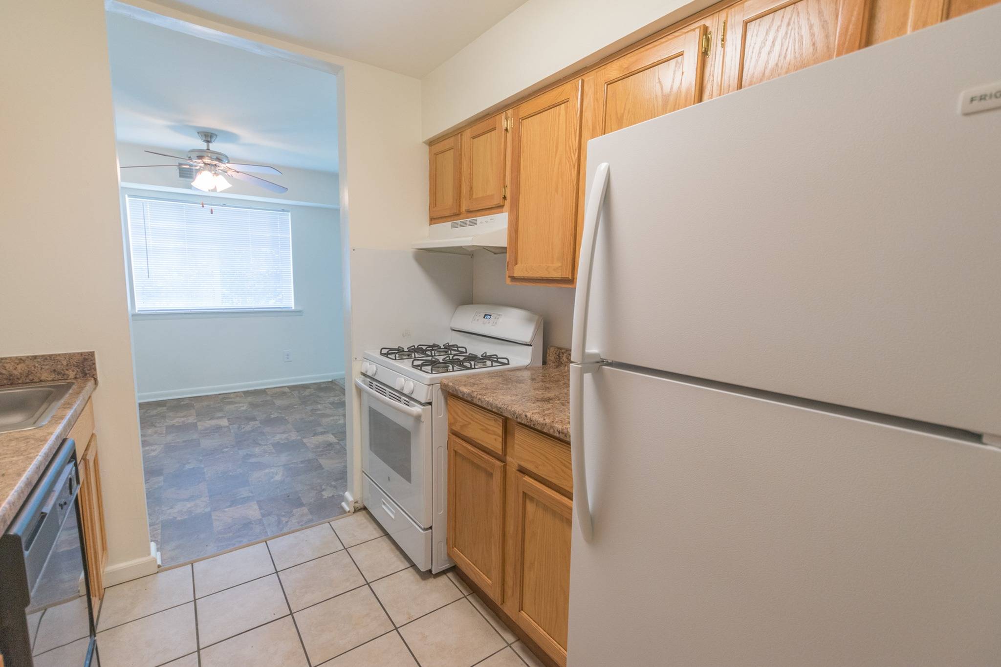 Kitchen area of an apartment, fitted with tiled flooring, spacious cabinets, and a stove