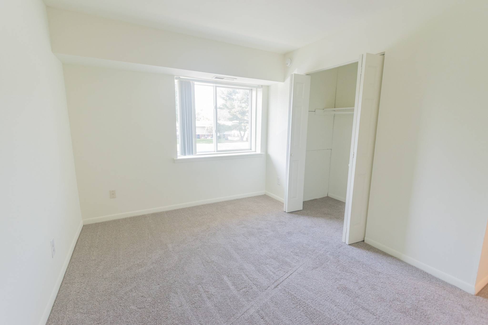 Bedroom area of an apartment unfurnished, fitted with carpet flooring, and a spacious closet
