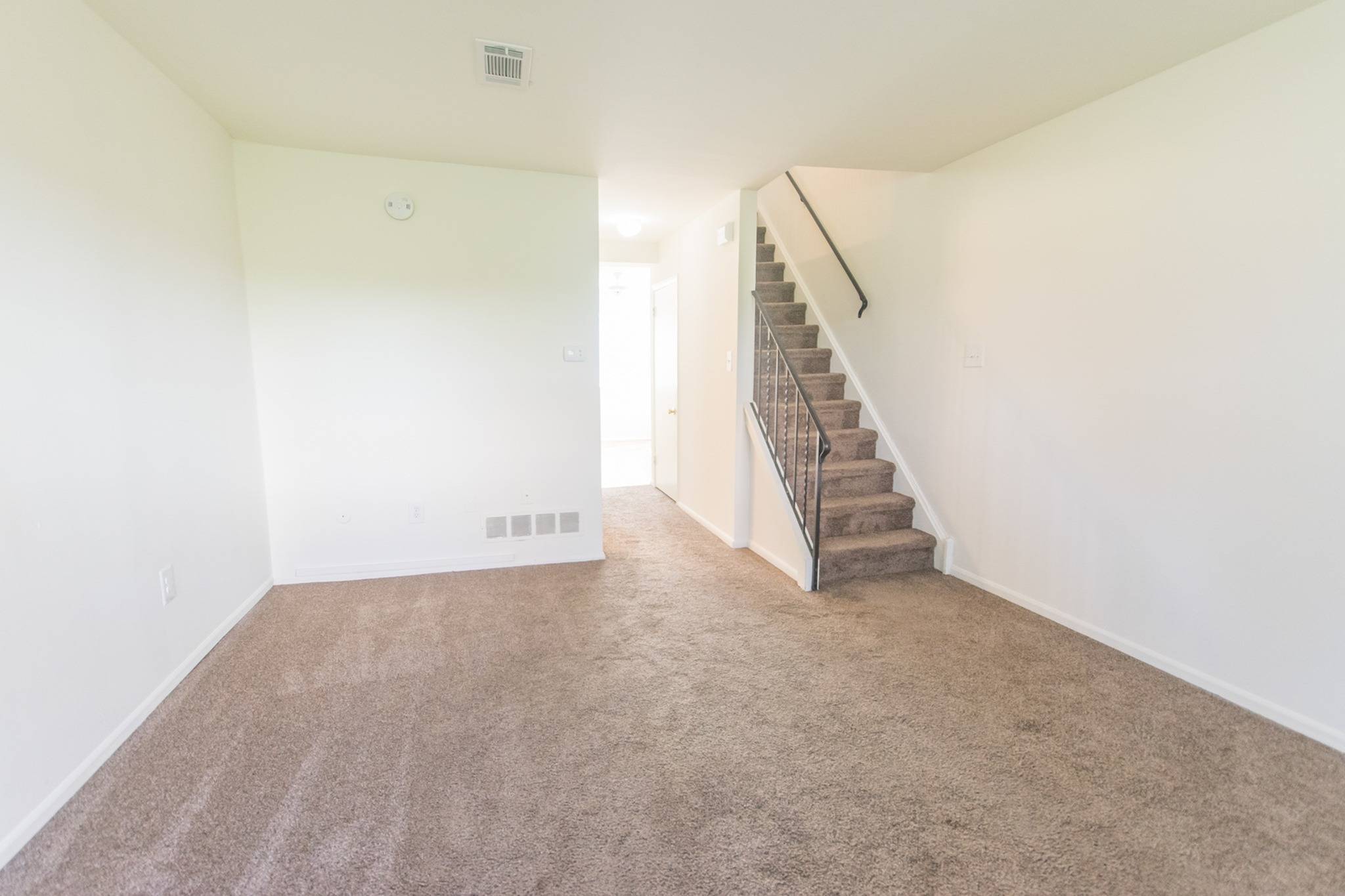 Carpeted living room and stairs at Rolling Glen Apartment and Townhomes