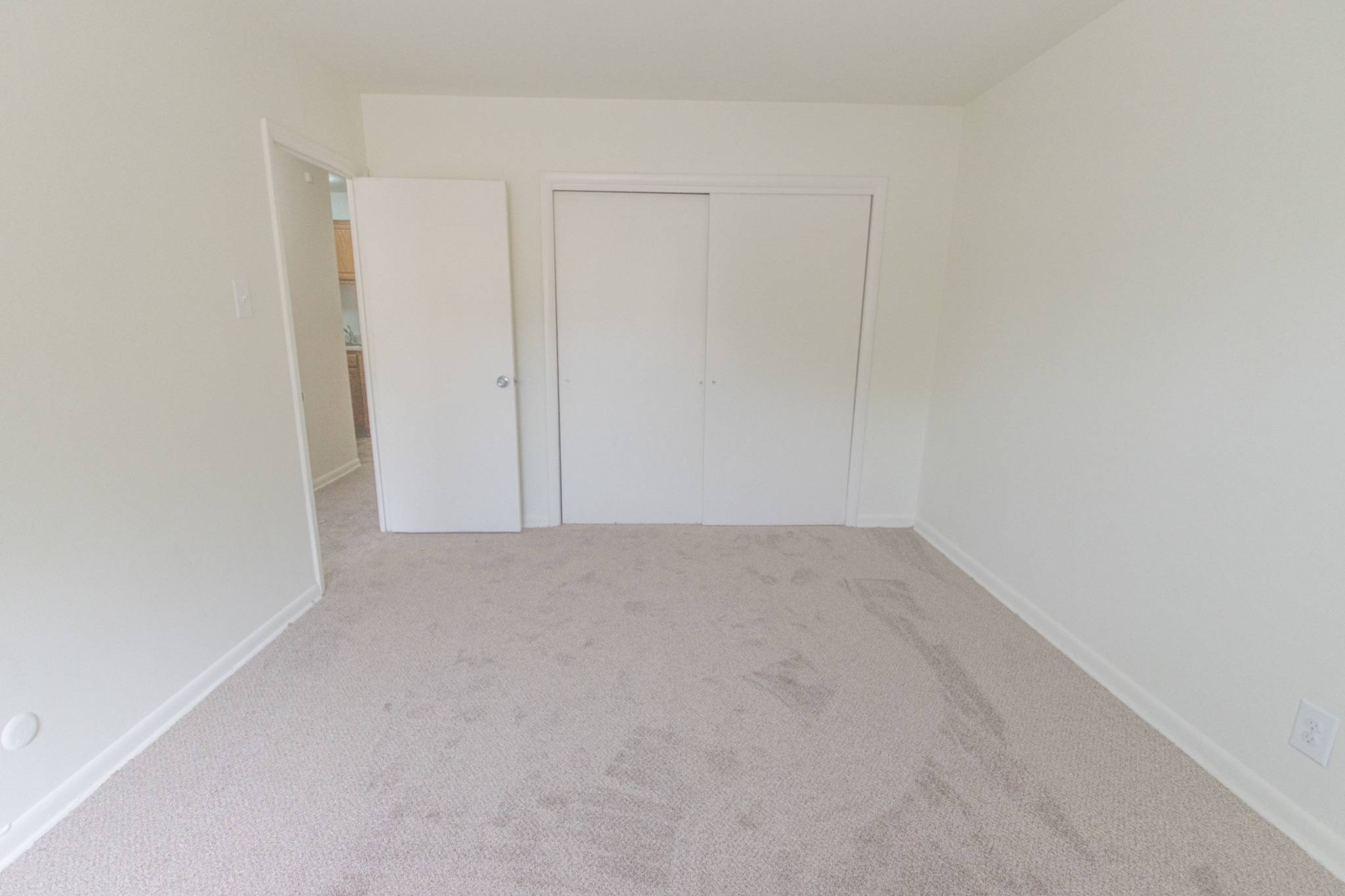 Bedroom with carpets and closet with sliding doors in an apartment at Lansdale Village Apartments.
