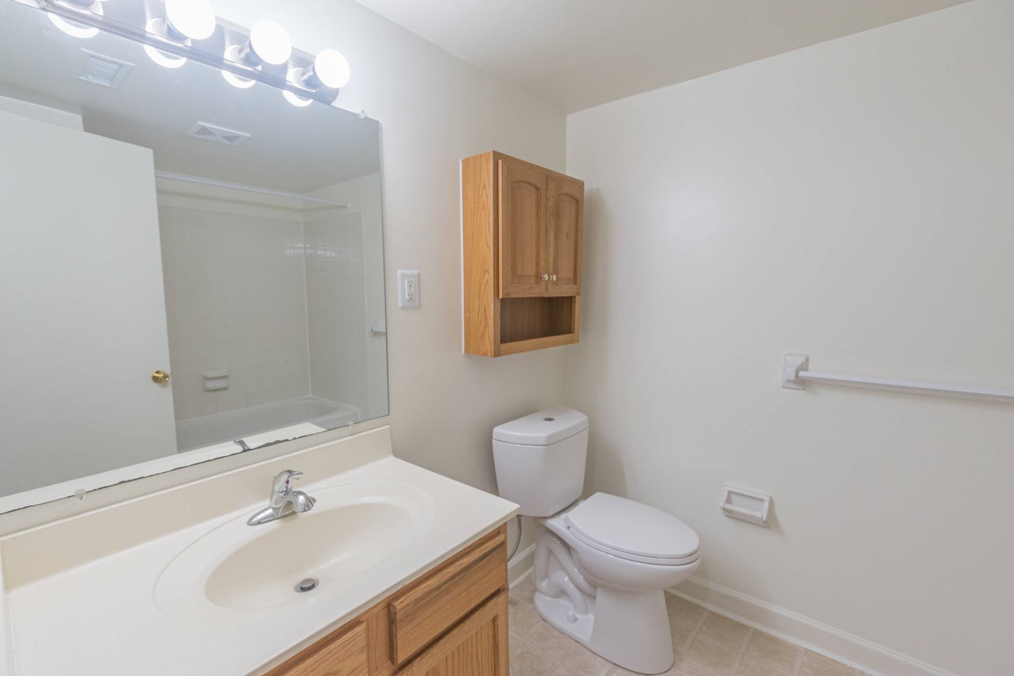 Bathroom with large mirror, toilet, and white countertops.