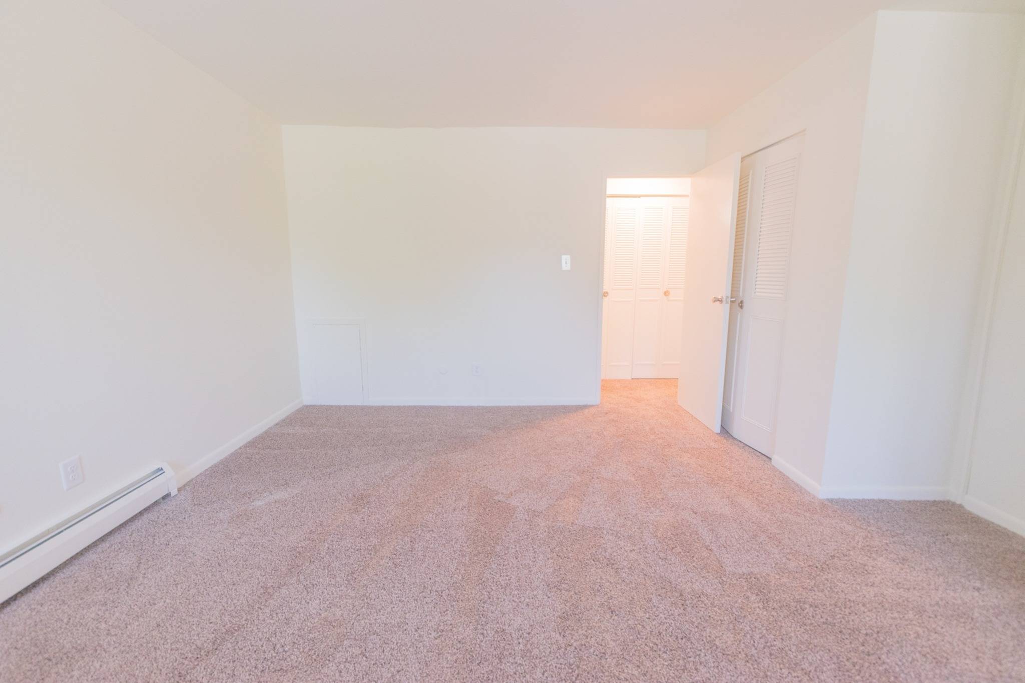 Bedroom area of an apartment unfurnished, fitted with carpet flooring, and a high ceiling