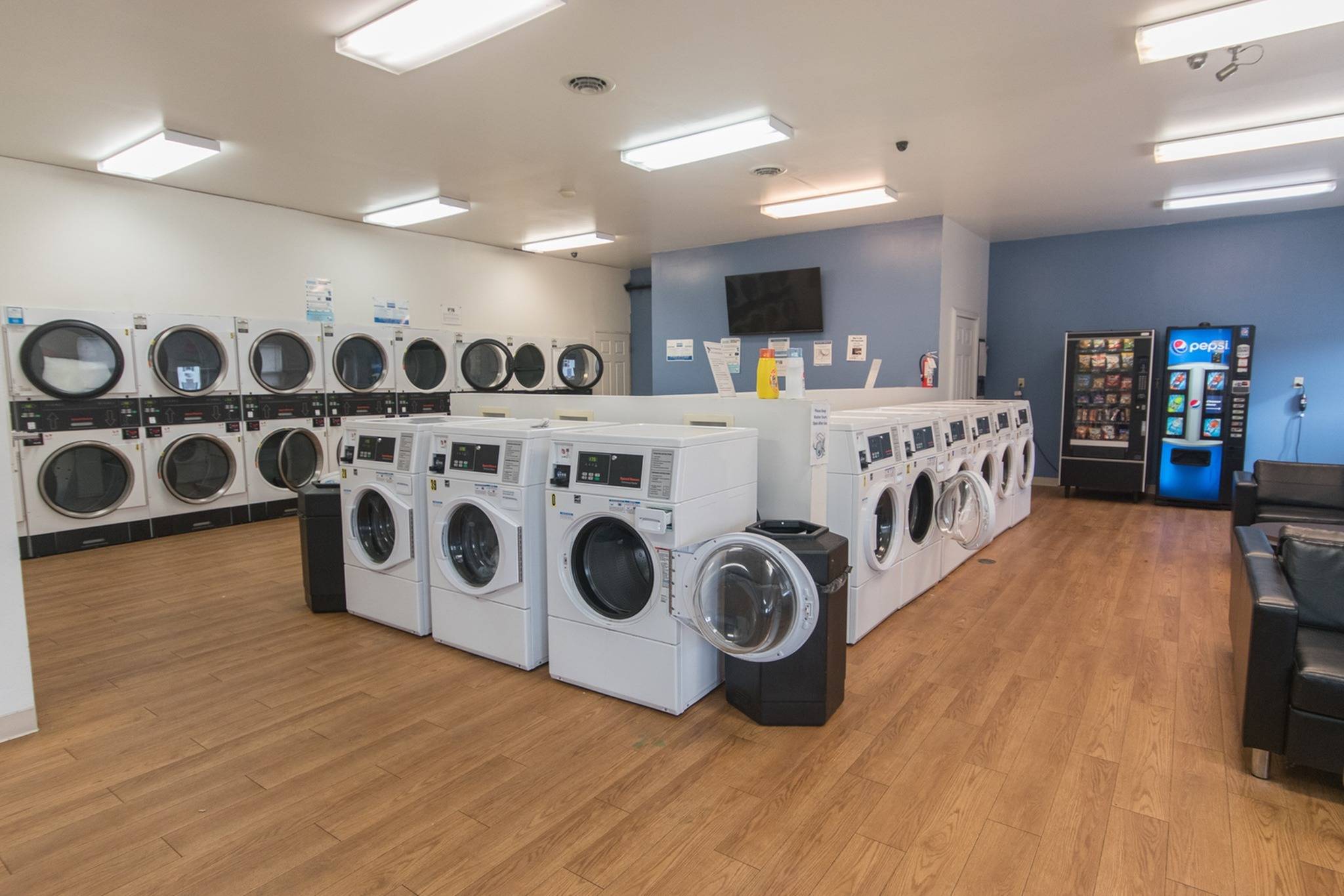 Several washer and dryers along with couches and vending machines.