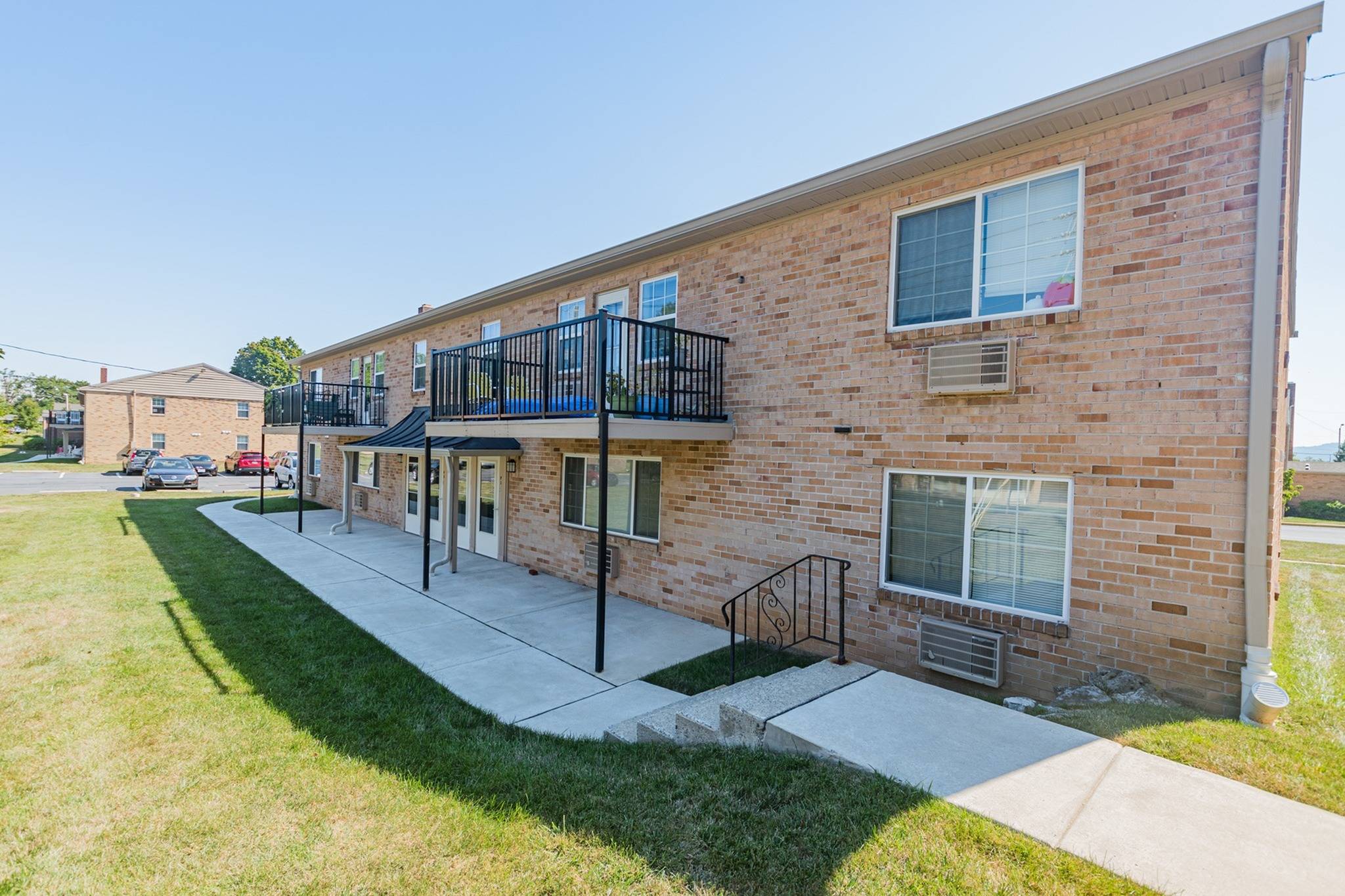 Woodland Plaza Apartments exterior with balconies and a pathway leading to apartment entrance