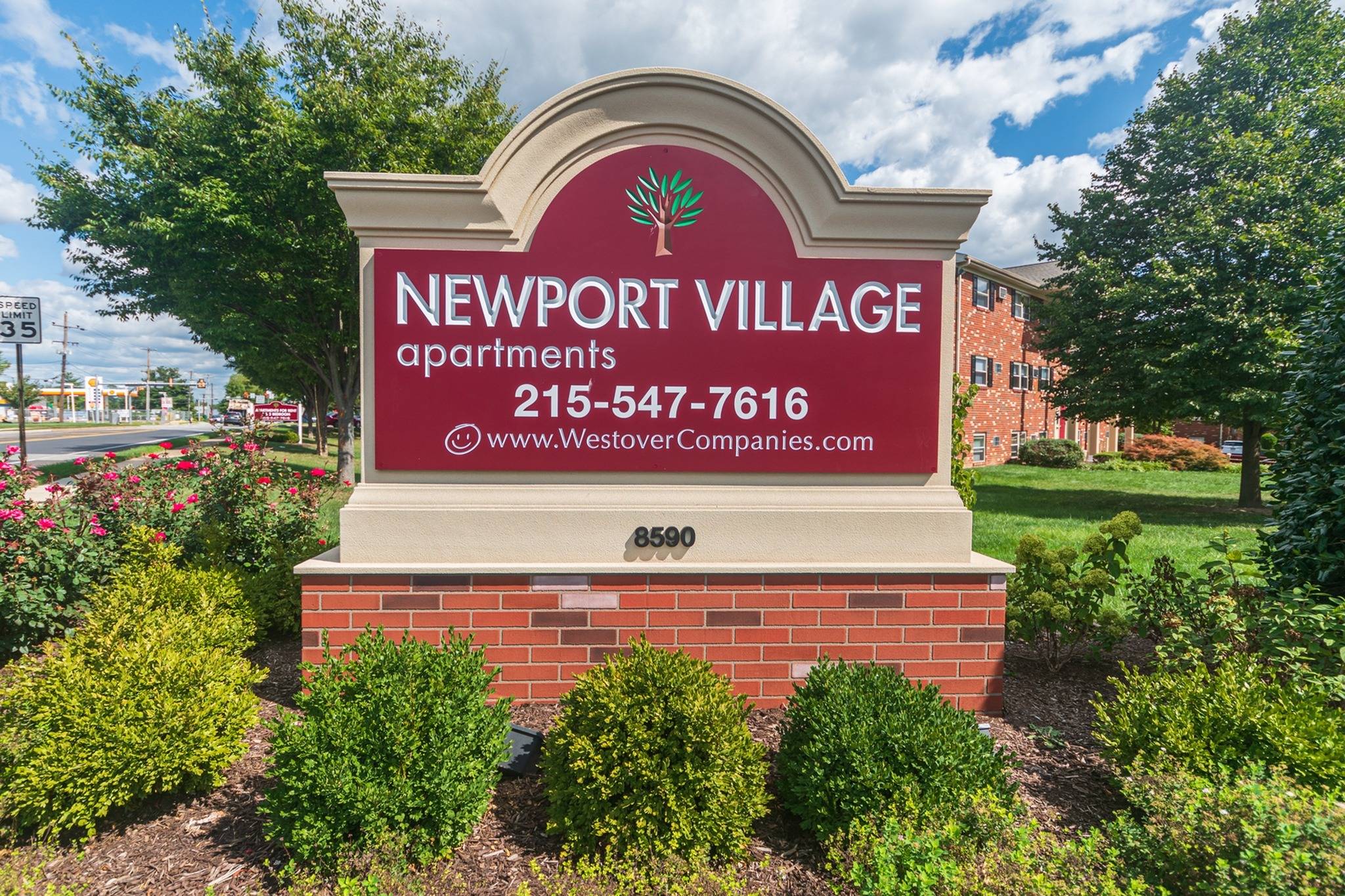 Newport Village Apartments sign with shrubs around the sign.