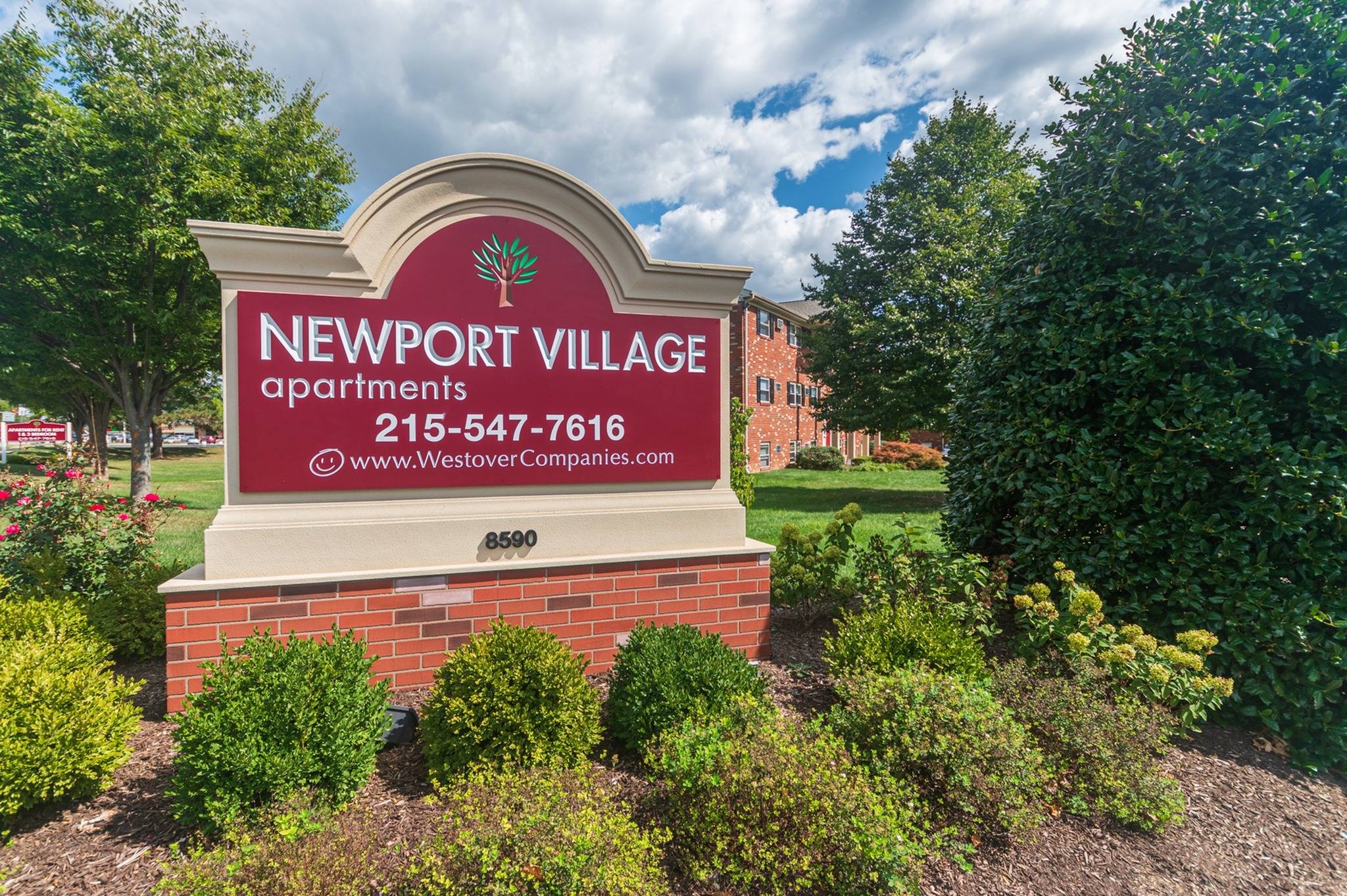 Newport Village Apartments sign with several shrubs in front of it.