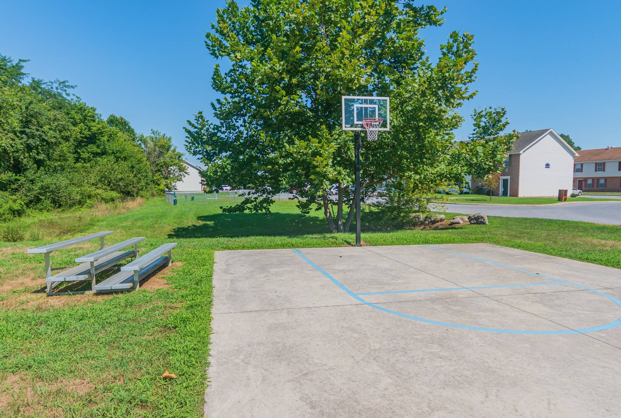 Basketball court with grass beside it.