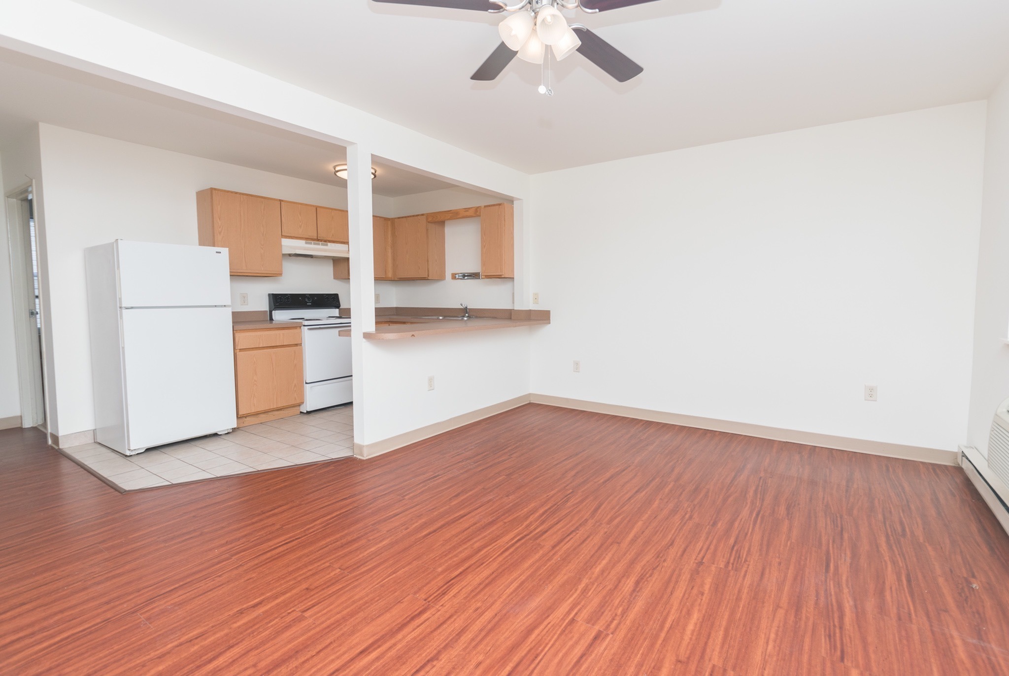 Spacious living and dining area with a ceiling fan next to the kitchen area.