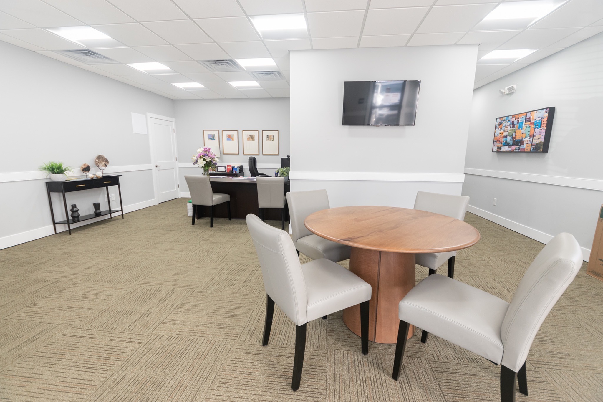 Leasing office with an office desk and a circular wooden table with four chairs.