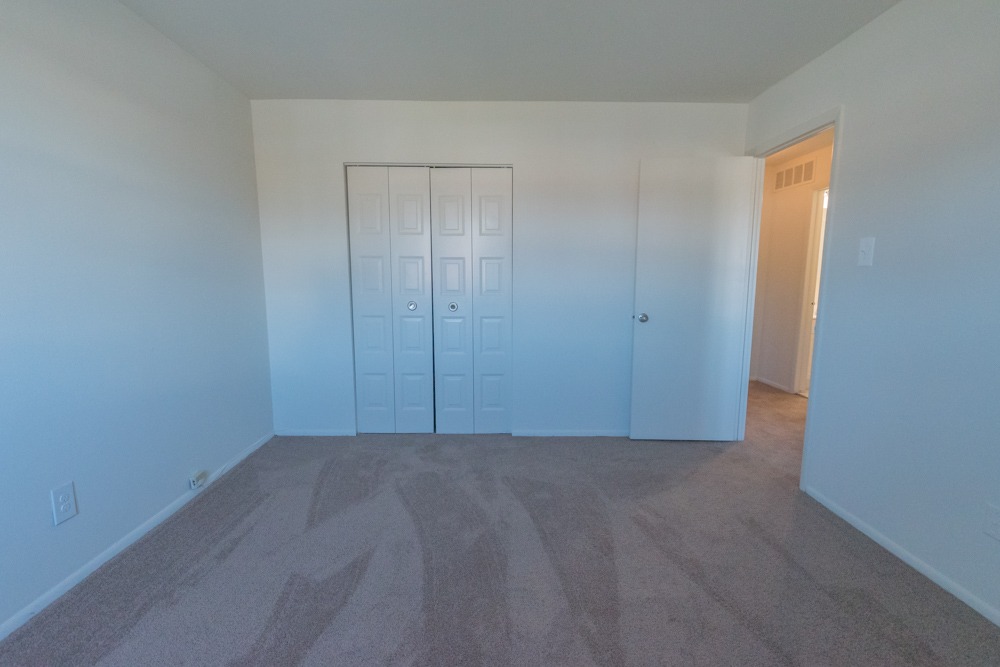 Carpeted bedroom with white walls and a closet.