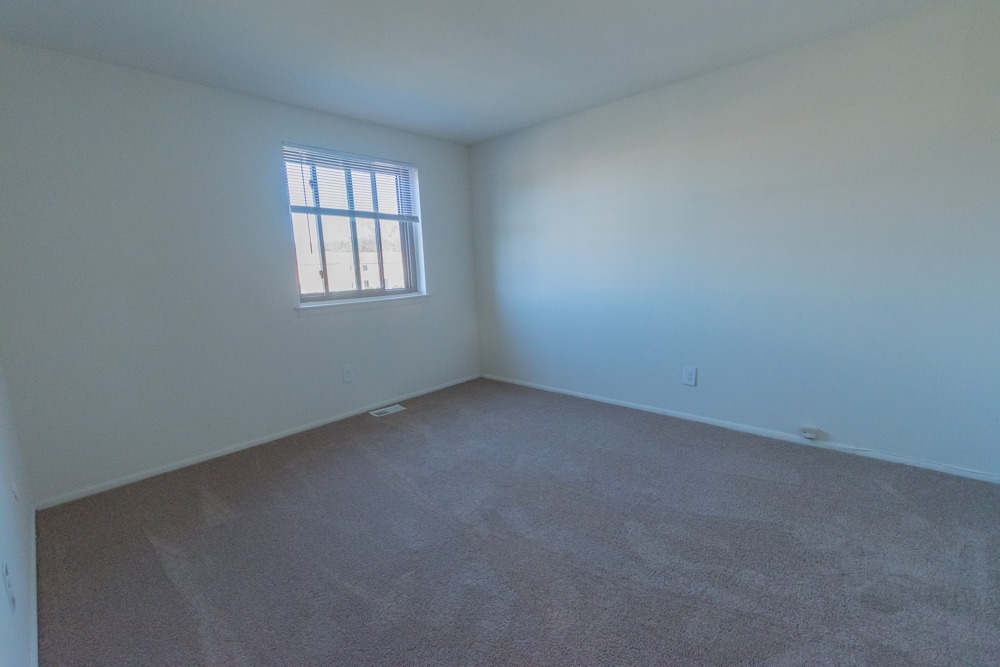 Bedroom with carpet, white walls, and a window.