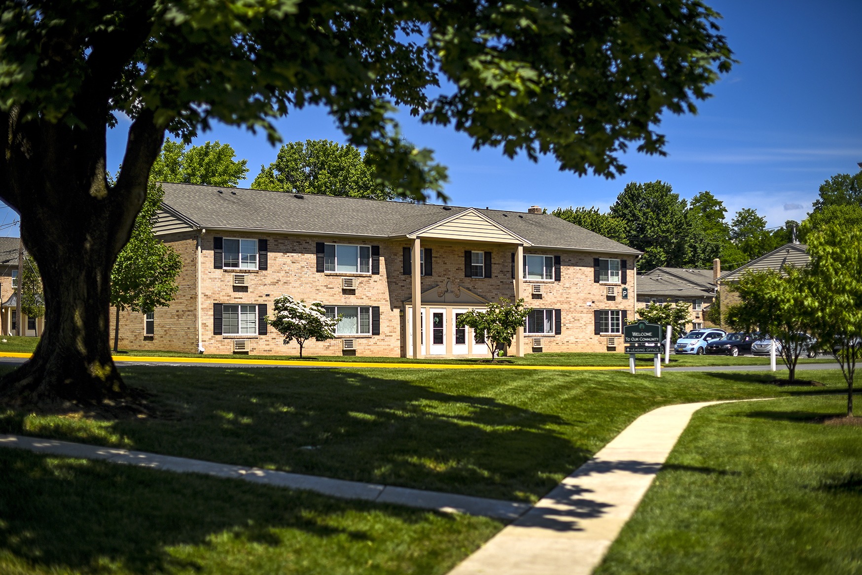 Apartment building of Woodland Plaza with a large tree and lawn in front of it