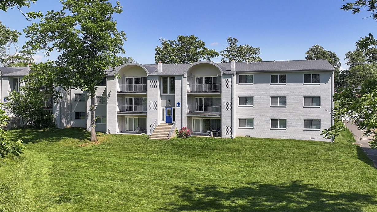 Grey apartment building with a large lawn in front of it