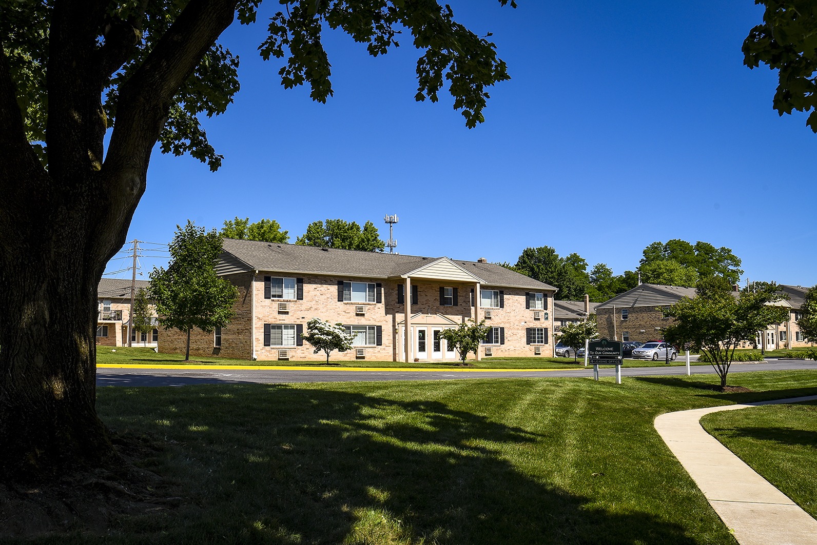 Lawn and exterior of Woodland Plaza Wyomissing apartments with a shaded lawwn in front