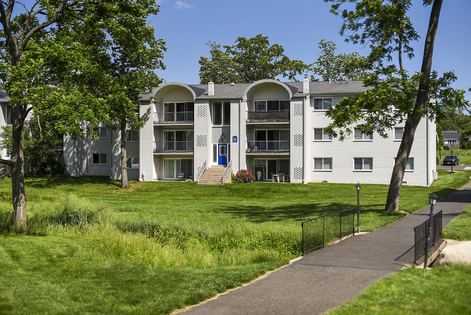 Lansdale apartment building on a large lawn with a paved walkway on the right